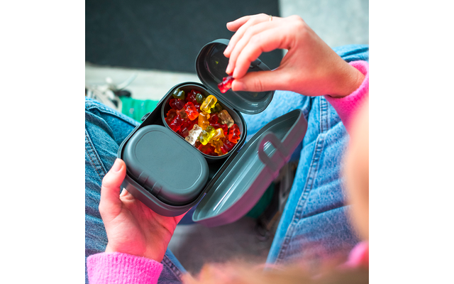 Mains tenant une boîte bento grise sur les genoux ; un compartiment ouvert montre des oursons en gelée colorés