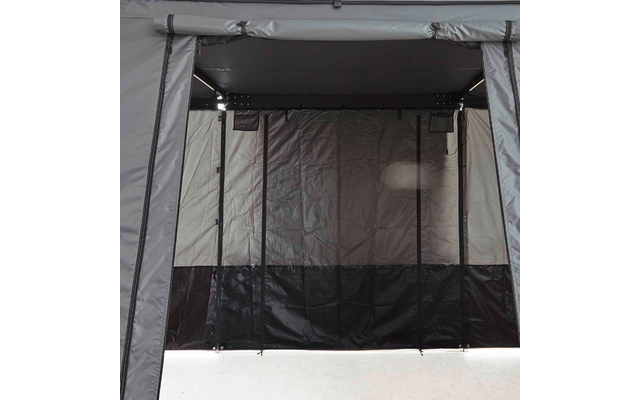 Innenraum mit grauen Textilwänden, dunkler unterer Wandverkleidung, drei senkrechten schwarzen Stangen oder Gurten, einer Metallstange oben, dünnen Leisten entlang der oberen Innenkante und heller Bodenfläche