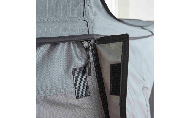 Nahaufnahme eines grauen Gewebepanels mit offenem Reißverschluss, Reißverschlusszug, Klettverschlussstücken, sichtbaren Nähten und schwarzer Einfassung