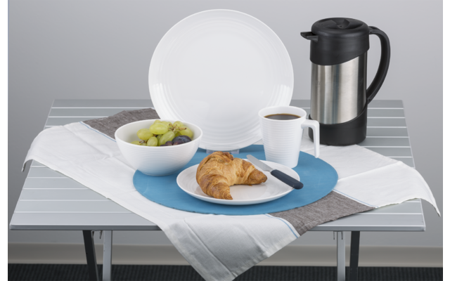 Ein gedeckter Tisch mit einem weißen Teller, auf dem Gebäck liegt, daneben eine Schale mit Oliven, ein Glas mit orangefarbener Flüssigkeit und eine Thermoskanne