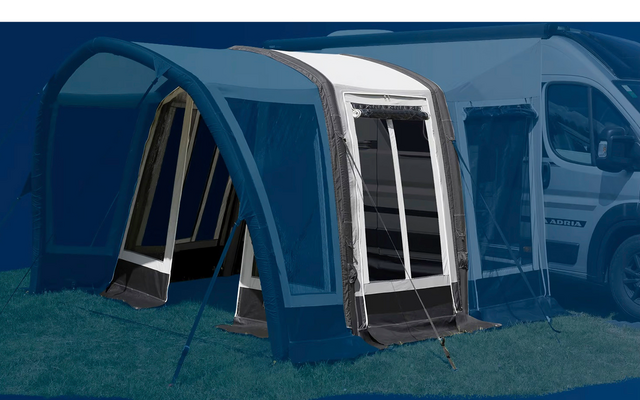 Blaues Vorzelt an einem weißen Wohnmobil auf einer grünen Wiese