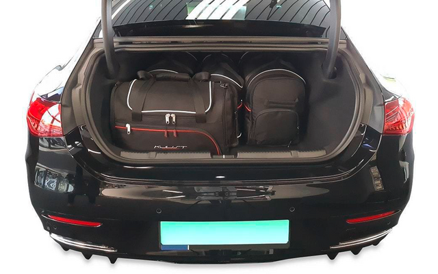 Coffre ouvert d'une voiture noire avec deux sacs de voyage et un sac à dos