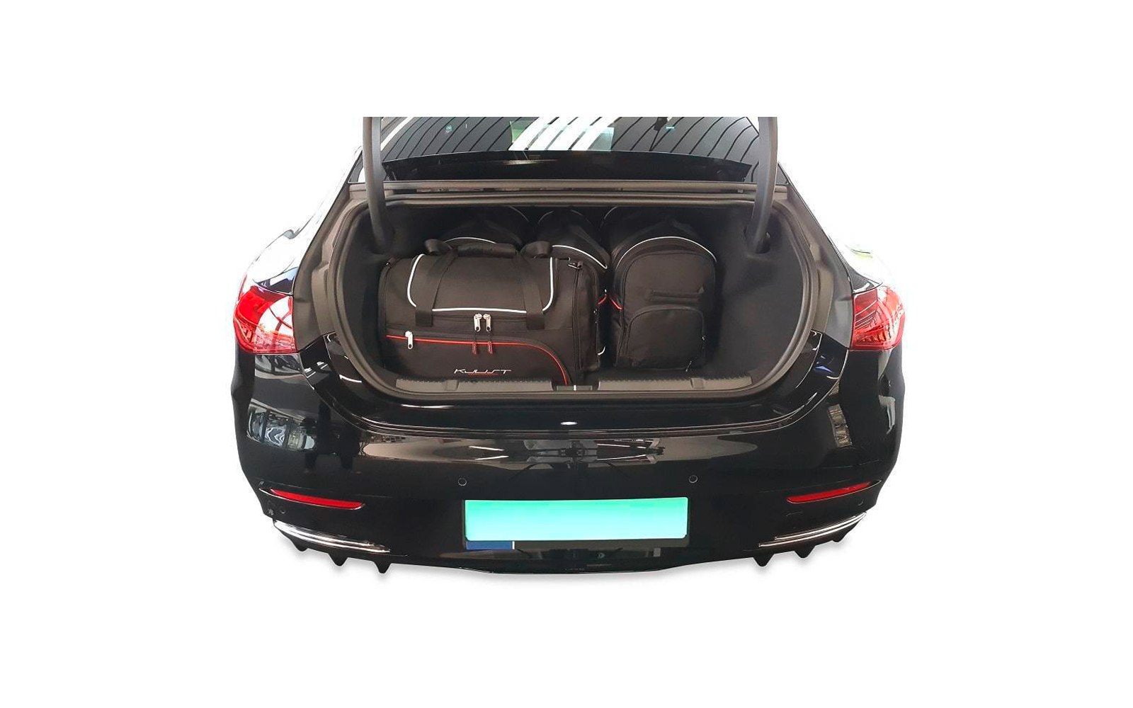 Coffre ouvert d'une voiture noire avec deux sacs de voyage et un sac à dos