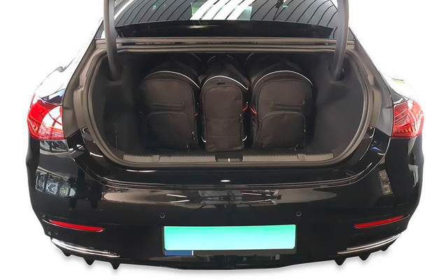 Coffre ouvert d'une voiture noire avec trois sacs à dos noirs à l'intérieur