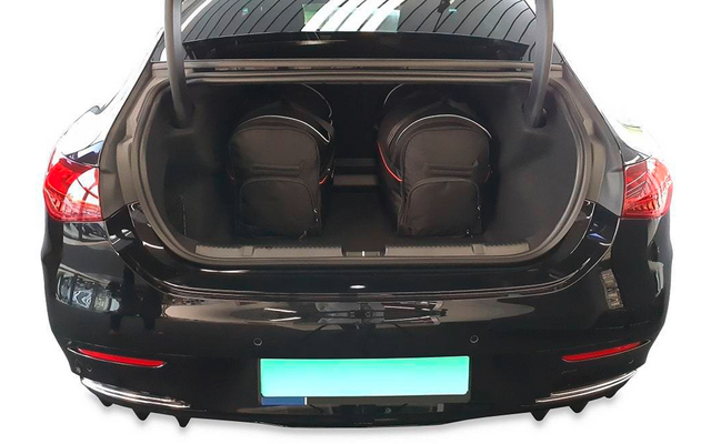 Coffre ouvert d'une voiture noire contenant deux sacs à dos noirs ; zone de la plaque d'immatriculation verte