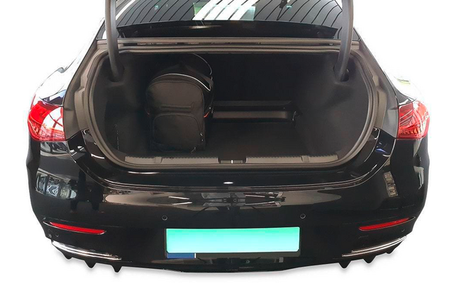 Coffre ouvert d'une voiture noire avec un sac à dos noir à l'intérieur ; feux arrière et plaque d'immatriculation floue visibles