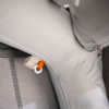 Nahaufnahme eines hellgrauen aufblasbaren Materials mit Reißverschluss, abgesteppten Nähten, einem weißen Plastikring mit orangefarbenem Zugband und einer karierten Innenfläche