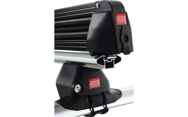 Deux supports noirs de barres de toit avec barres transversales noires sur un toit de voiture clair, avec étiquettes de marque rouges