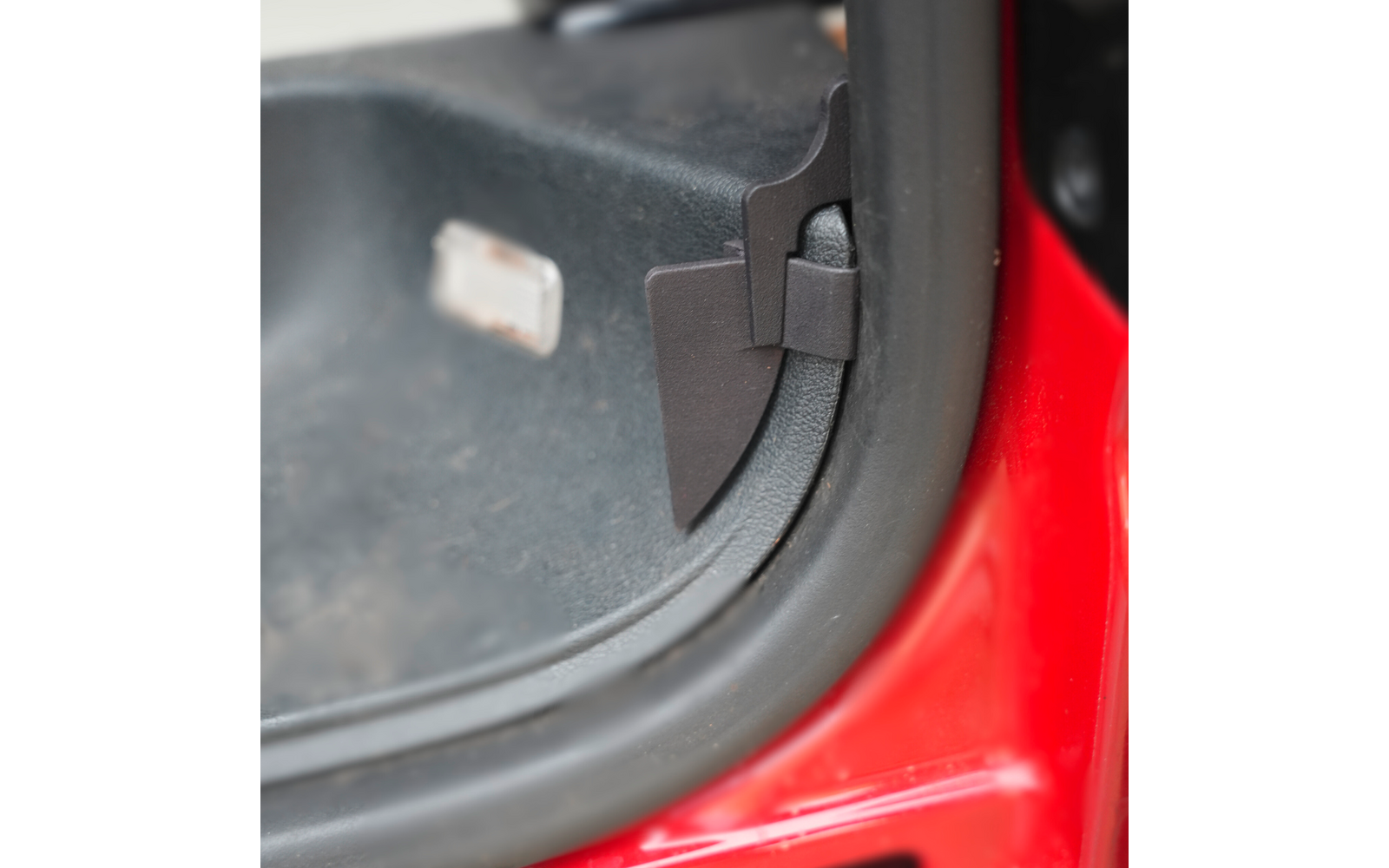 Innenraum eines roten Autos mit geöffnetem Kofferraumdeckel, Sicht auf den schwarzen Kofferraumbereich