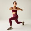 Persona con ropa deportiva burdeos, pierna delantera doblada, pierna trasera estirada, brazos sobre el pecho, zapatillas claras, fondo claro