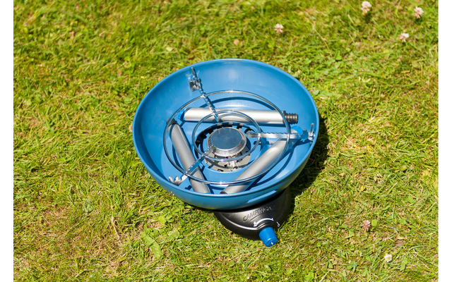 Blauwe eenpit gasbrander met ronde pannendrager en blauwe aansluiting op gras