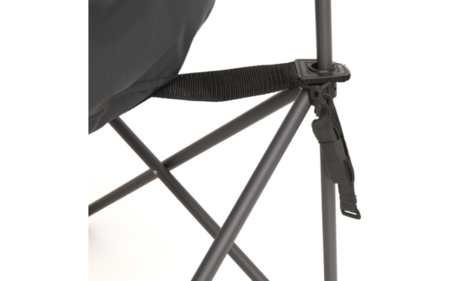 Nahaufnahme eines Klappstuhls: schwarzer Stoff, schwarzer Gurt mit Schnalle, graue gekreuzte Metallstangen