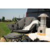 Gray padded armchair with blanket and footstool in the garden, next to a lantern on a table