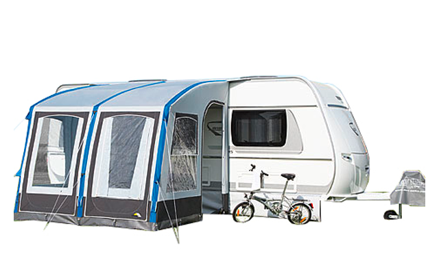 Caravana blanca con toldo gris, una bicicleta y accesorios de bicicleta al frente