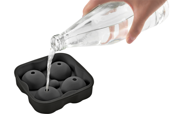 Hand gießt Wasser aus einer Flasche in einen Eiswürfelbehälter