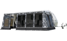 Großes graues und weißes Wohnwagenvorzelt auf einer grünen Wiese mit Bäumen im Hintergrund