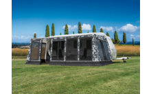 Large gray and white caravan awning on a green lawn with trees in the background