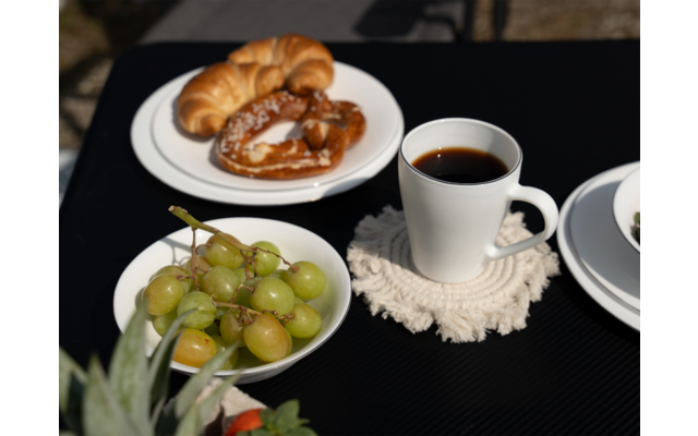Ein Tisch mit einer Tasse Kaffee, einem Teller mit Croissants und einem Teller mit Trauben