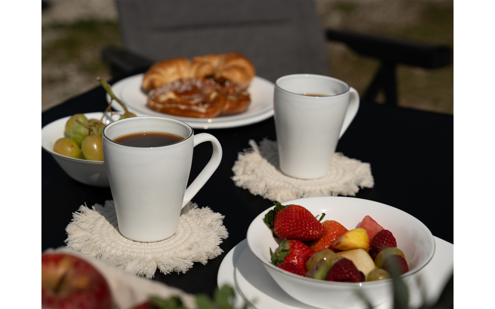 Tisch mit zwei weißen Tassen, einem Teller mit Früchten und einem Teller mit gebratenem Essen