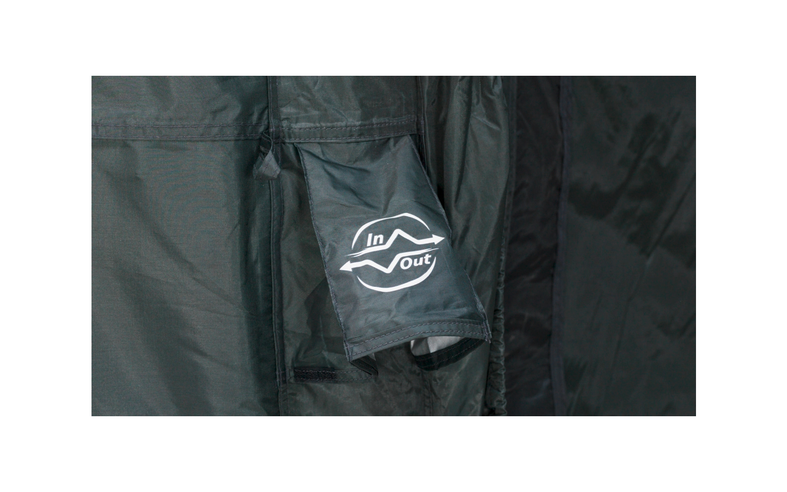 Dunkelgrüner Stoff mit Ärmel und Tasche, weißes ‚In/Out‘-Logo