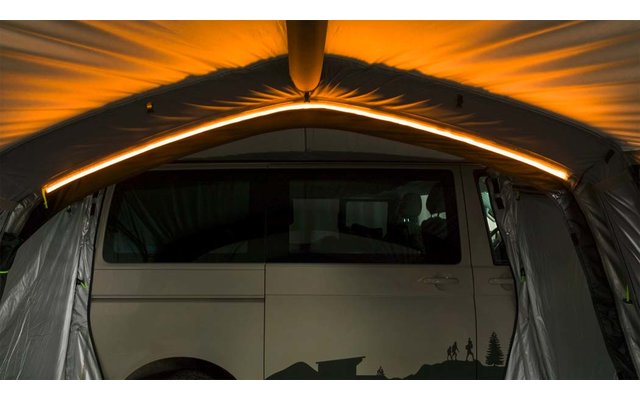 Teilansicht eines weißen Vans hinter einer geöffneten grauen Stofföffnung; orangefarbene Lichtleiste am oberen Bogen
