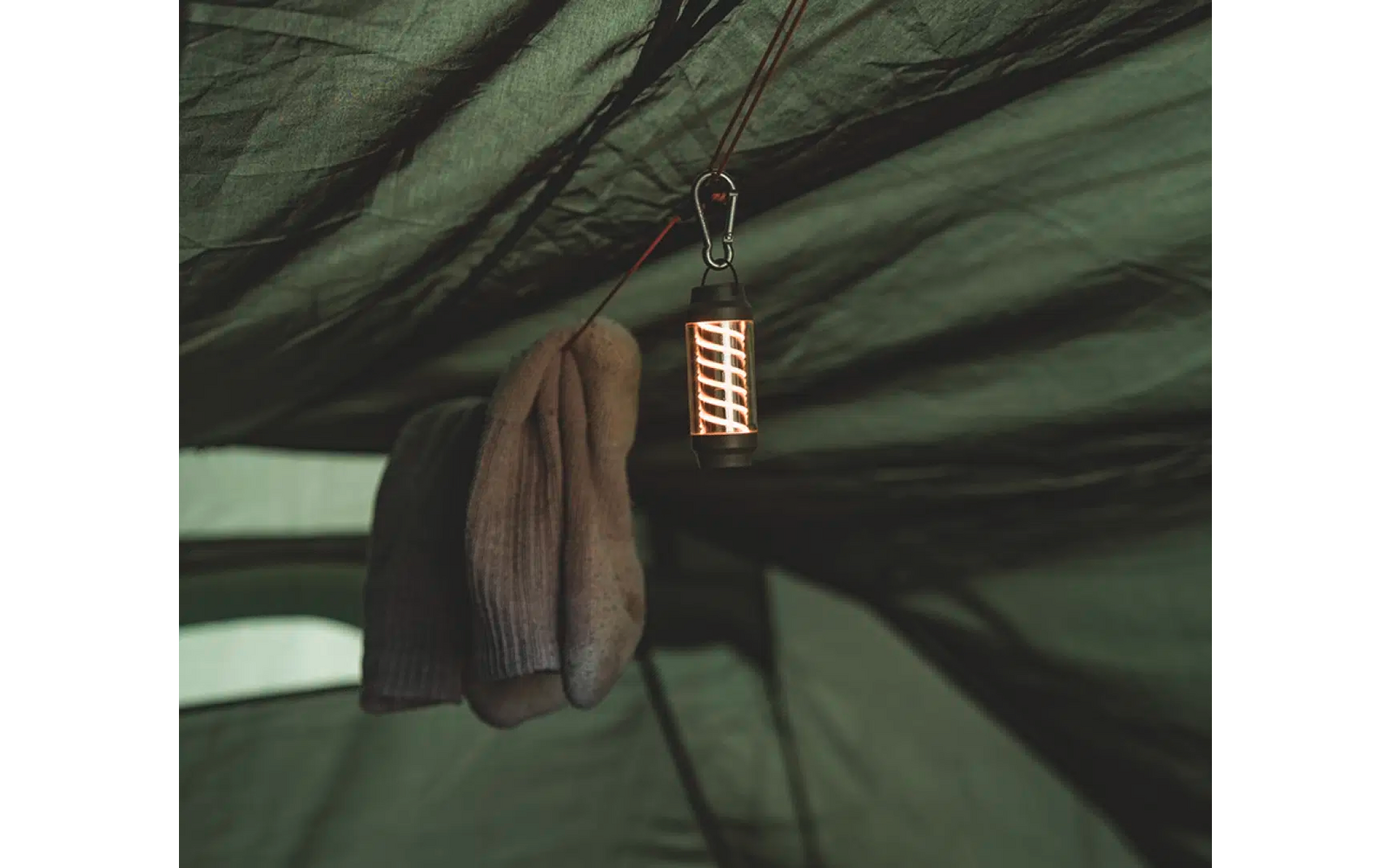 Braune Handschuhe hängen an einem grünen Zelt