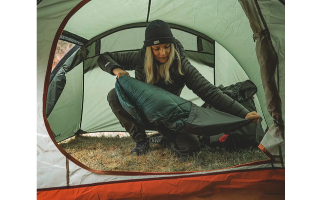 Person sitzt in einem Zelt und schaut nach draußen