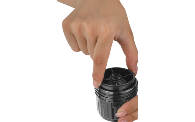 Pièce cylindrique noire en plastique avec papier blanc posé dessus, sur une boîte blanche devant un fond clair