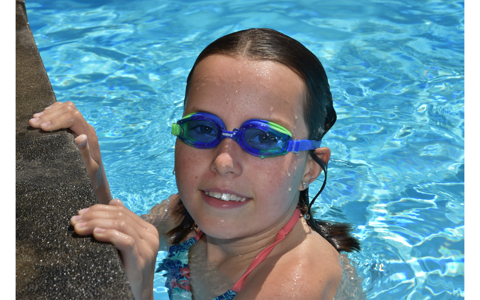 Person mit nassen Haaren und blauen Schwimmbrillen im Wasser