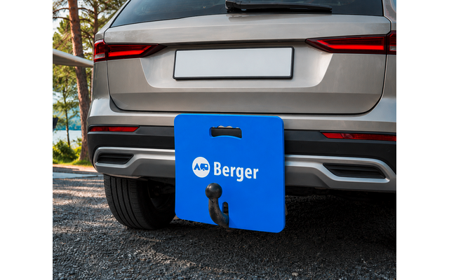Achterkant van een zilverkleurige SUV met een witte kentekenplaat, een blauw bord met 'Berger' voor de trekhaak, zichtbare trekhaakkogel, asfalt en bomen op de achtergrond
