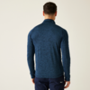 Ein Mann von hinten, trägt einen dunkelblauen Pullover und eine dunkle Hose