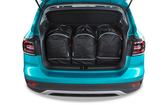 Coffre ouvert d'une voiture turquoise contenant trois sacs à dos noirs côte à côte