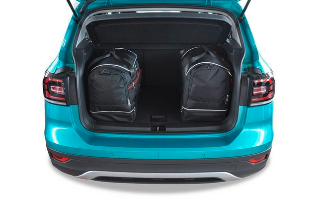 Coffre ouvert d'une voiture turquoise avec deux sacs à dos noirs à l'intérieur