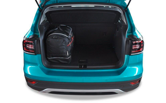 Coffre ouvert d'une voiture turquoise avec un sac à dos noir à accents rouges sur le côté gauche