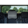 Car rear seat with a gray pad on the center headrest, black seats, visible seat belts and rear window showing trees