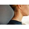 Side view of a person's neck with hair tied up, silver necklace, ear, black top and gray car headrest
