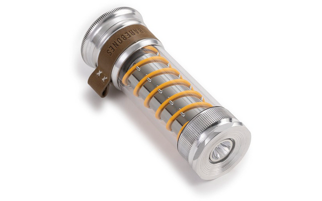 Cilindrisch metalen omhulsel met een doorzichtige buis waarin een gele spiraal zichtbaar is, metalen doppen aan beide uiteinden, klein leren lipje aan één zijde