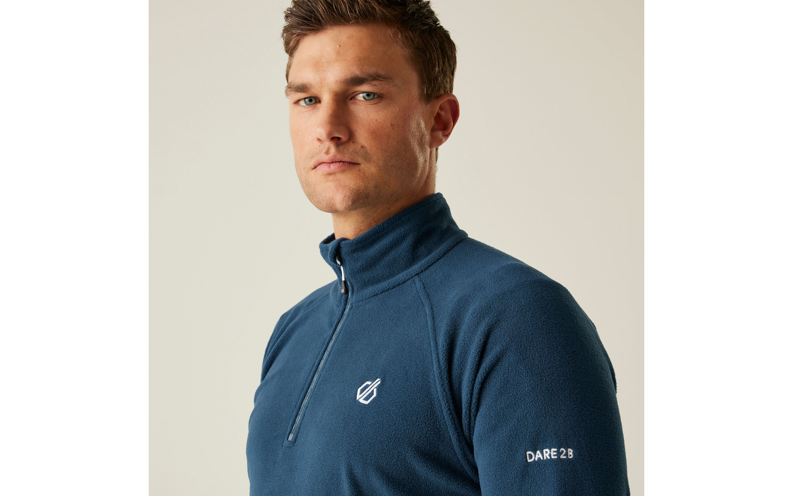 Porträt eines Mannes mit kurzem blonden Haar, der einen blauen Pullover mit Reißverschluss trägt