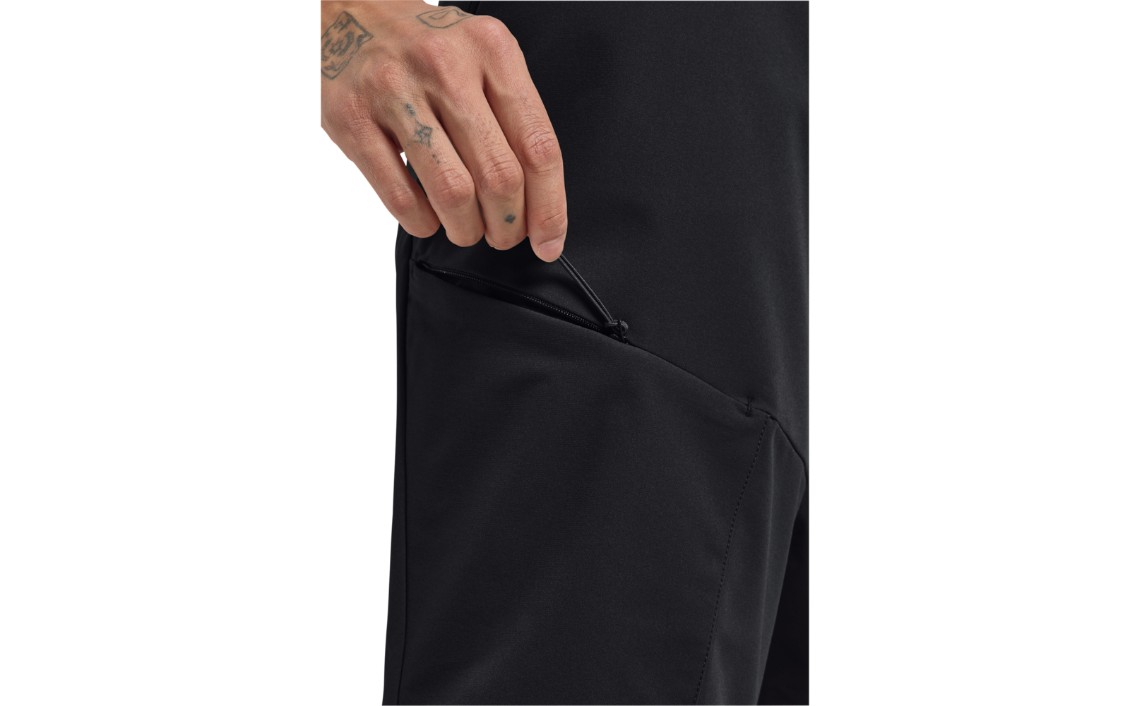 Hand mit Tätowierungen an einer teilweise geöffneten Reißverschlusstasche einer schwarzen Hose