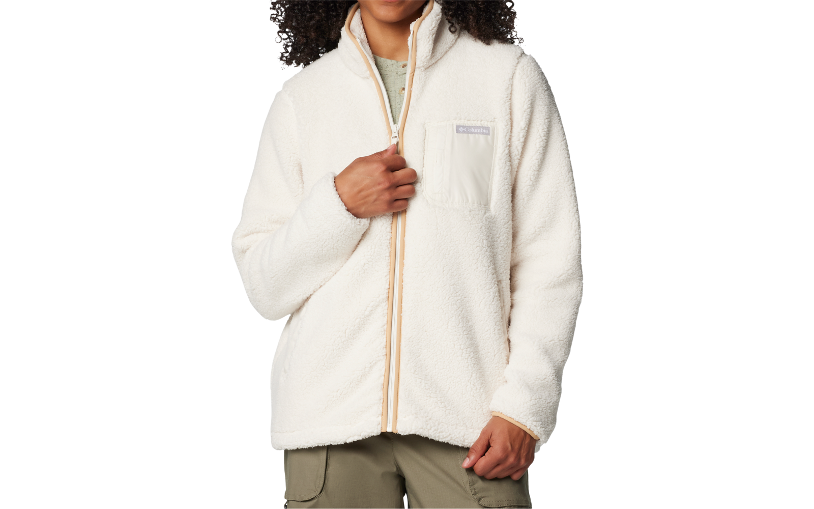 Personne aux cheveux épais et bouclés, portant une veste polaire blanche zippée, une main tient la fermeture éclair, sur fond blanc