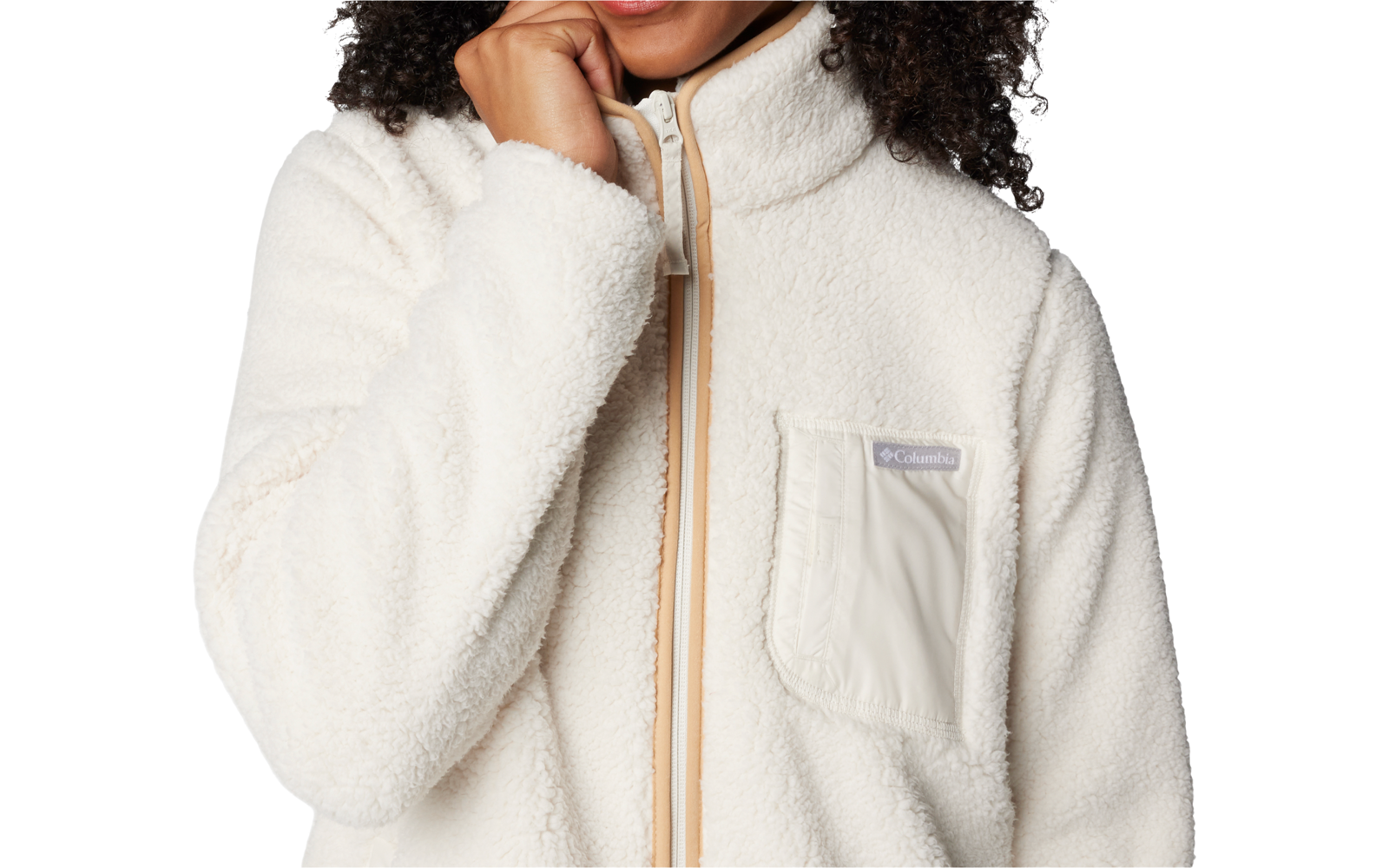 Gros plan d'une personne aux cheveux bouclés et foncés portant une veste polaire blanche avec fermeture éclair et poche poitrine ; une main touche le menton ; fond blanc