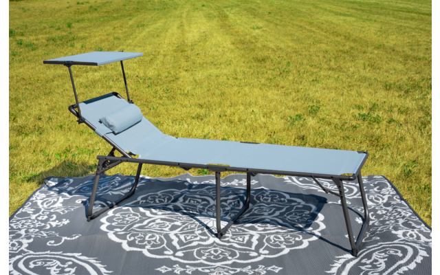 Lettino prendisole grigio-blu con cuscino su tappeto grigio a motivo bianco su prato verde