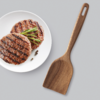 Gegrillte Frikadellen auf einem weißen Teller neben einem Holzwender