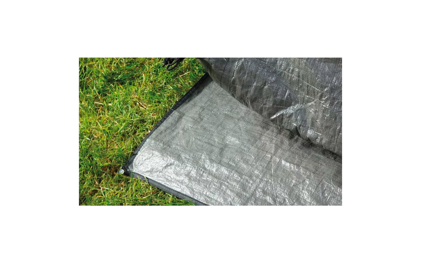 Eine zusammengefaltete graue Plane liegt auf grünem Gras