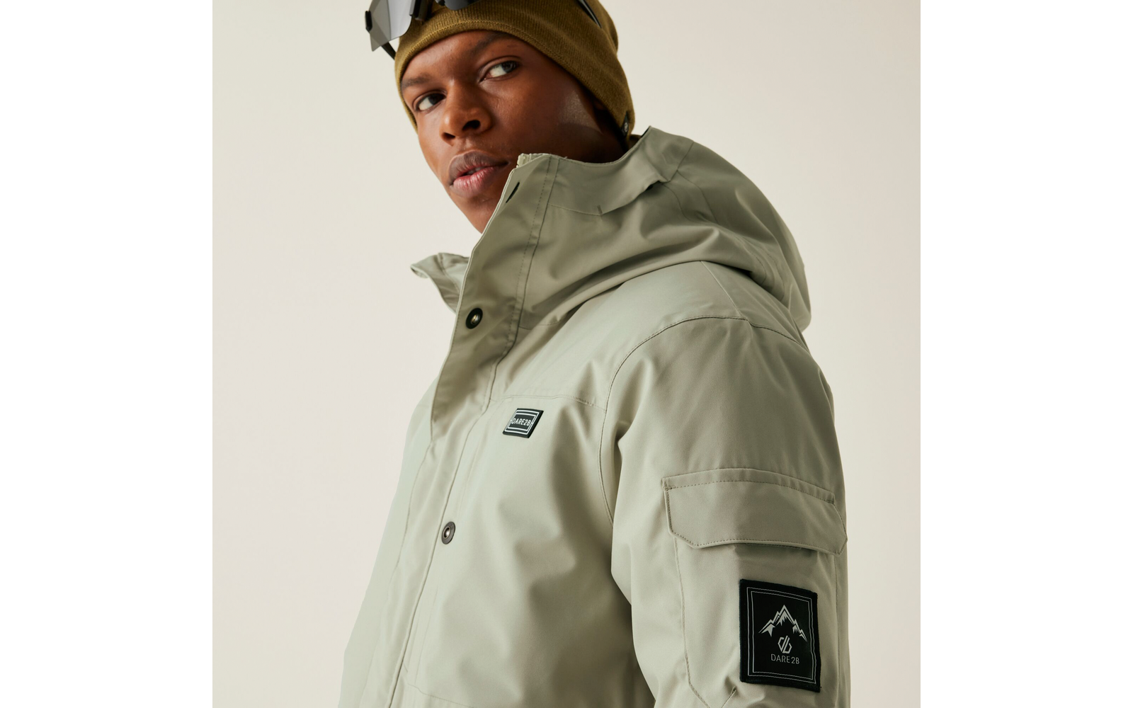 Ein Mann trägt eine beige Jacke und eine braune Mütze