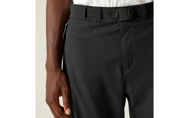 Plano detalle de cintura y mano, pantalones negros con bolsillo lateral con cremallera, cinturón negro, prenda blanca en la cintura