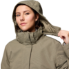 Frau in olivgrüner Jacke mit Kapuze, die Kapuze mit der linken Hand hält