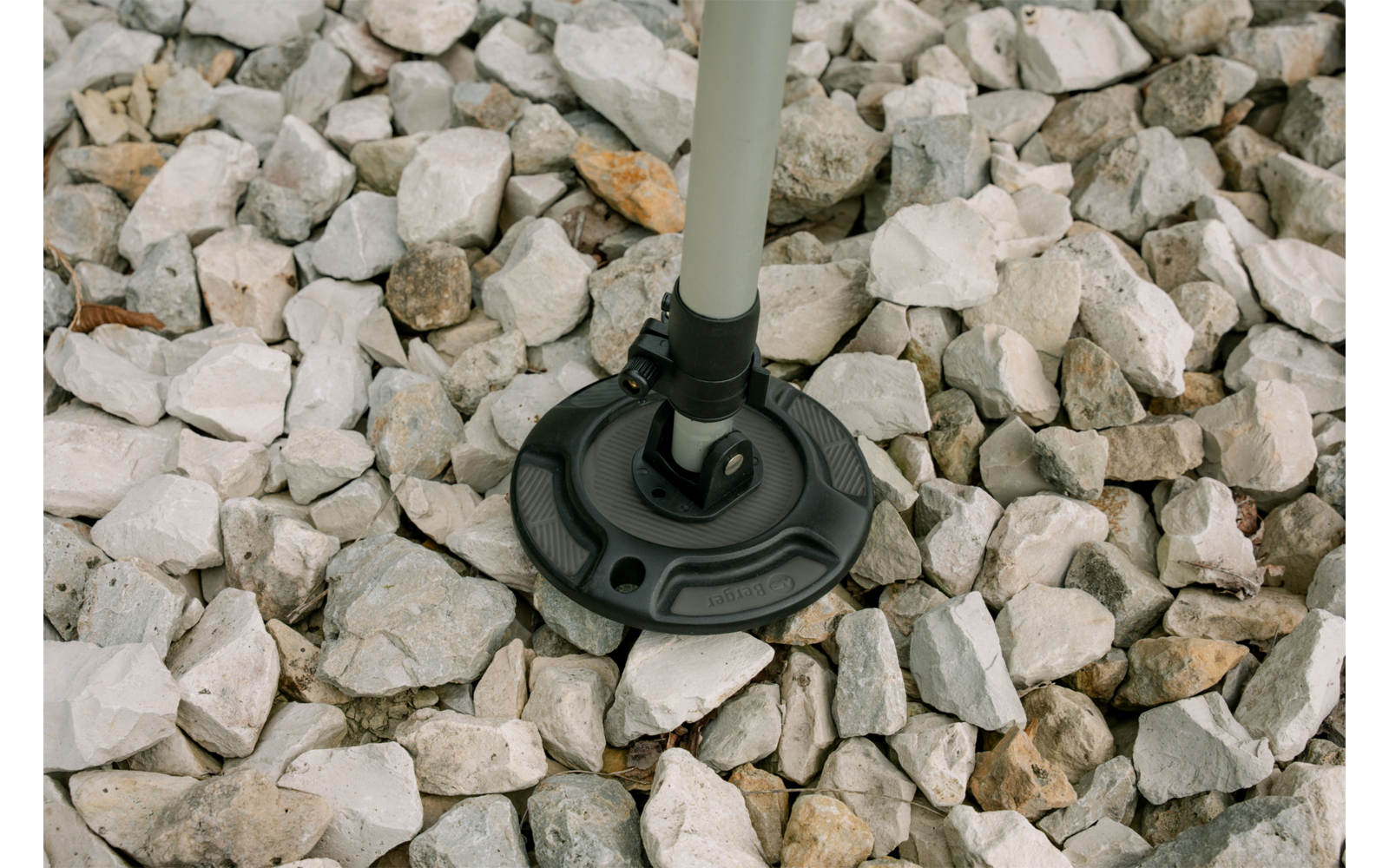 Objet rond noir sur une tige de couleur claire posé sur des cailloux blancs et gris
