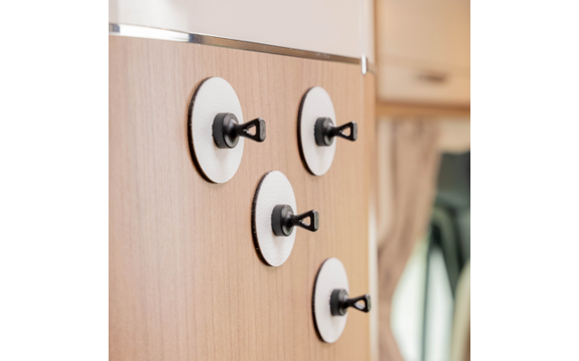Four round white discs with black plastic hooks on a wooden panel