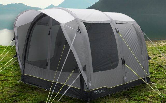 Zelt auf einer grünen Wiese mit See und Bergen im Hintergrund